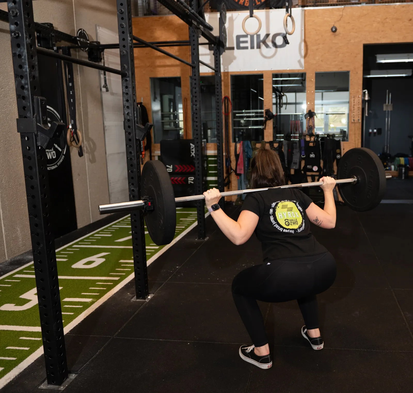 Athletin beim Back Squat mit Langhantel im Power Rack der Halle Zwo Badem