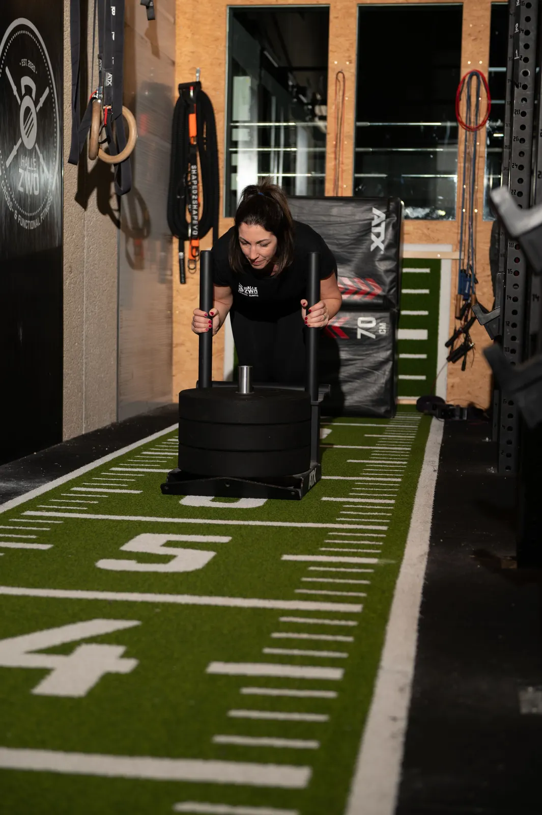 Frau beim Sled Push auf der Sprintbahn im Functional Fitness Studio Halle Zwo Badem